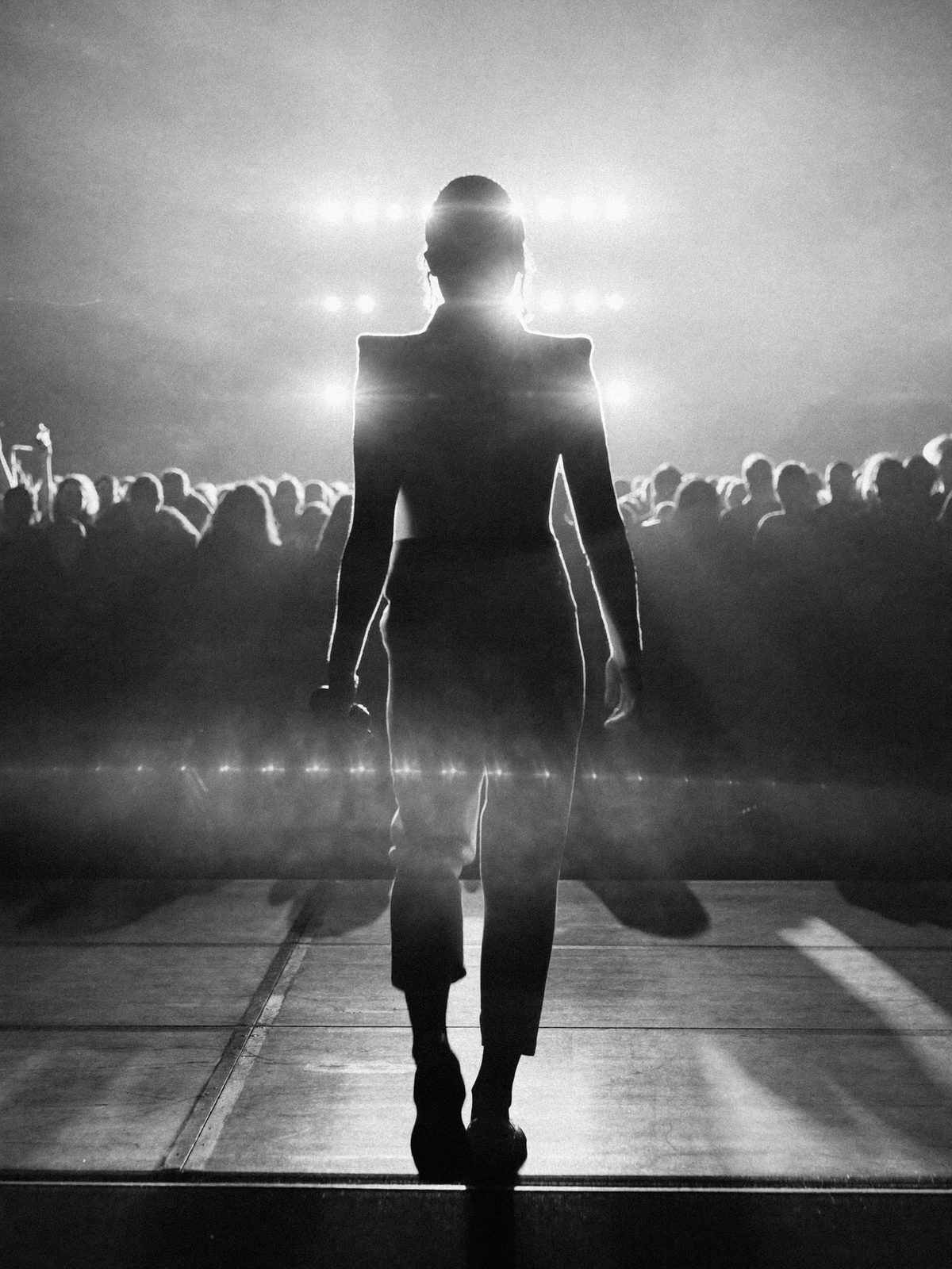 A performer walking toward blinding stage lights