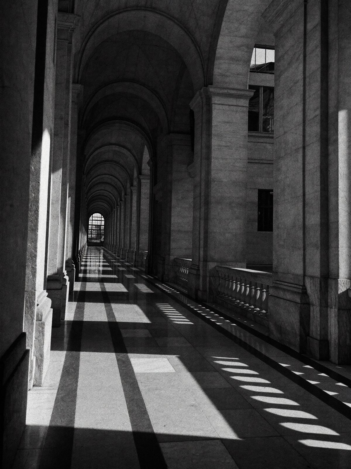 A grand marble corridor cut by shafts of daylight